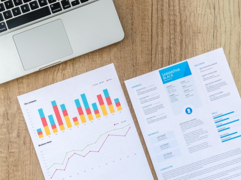 papers with charts and graphs on table with laptop