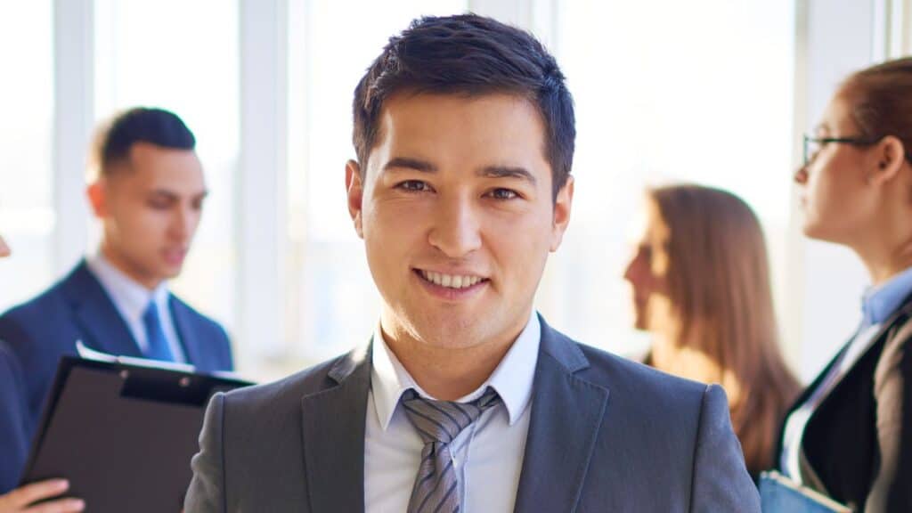A man smiles into the camera in a business suit and tie.