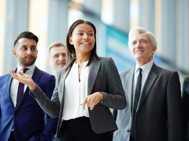 Professional leader speaking confidently while walking with colleagues in a workplace setting