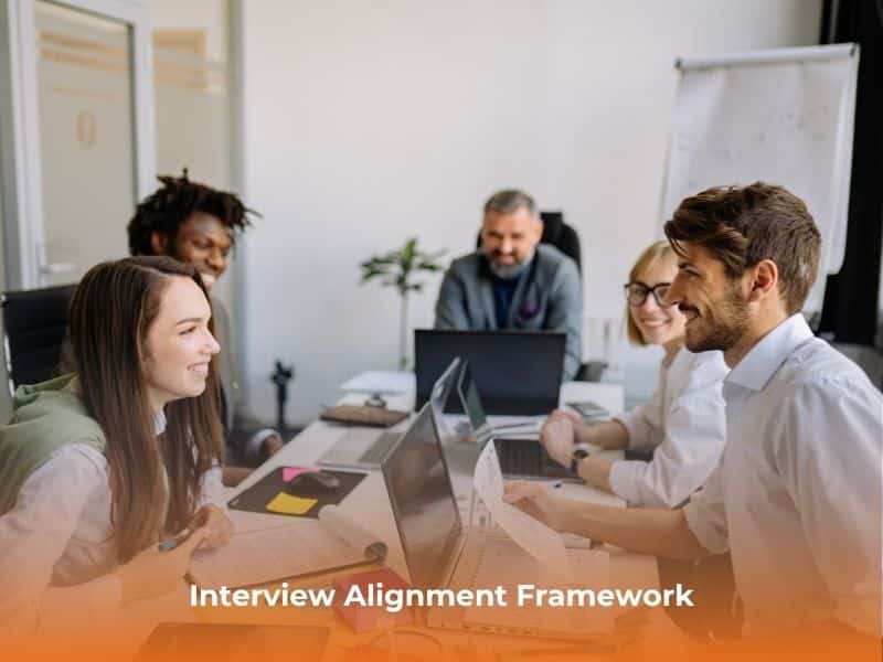 A group of professionals collaborate about interview techniques prior to an interview, sitting around a conference table.